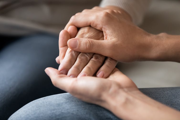 Close up of young woman holding hand of older woman