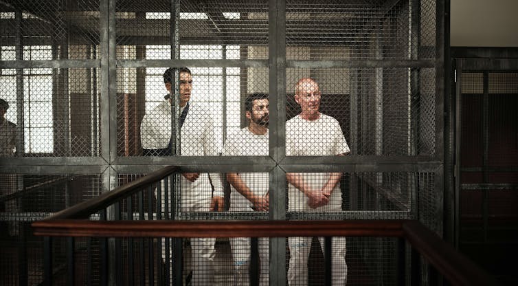 Three men behind bars.