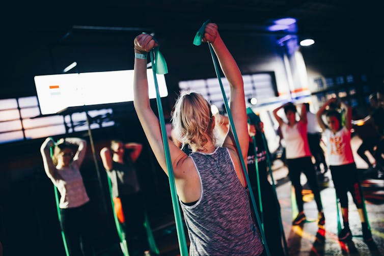 group of women exercising indoors using stretchy bands to add resistance