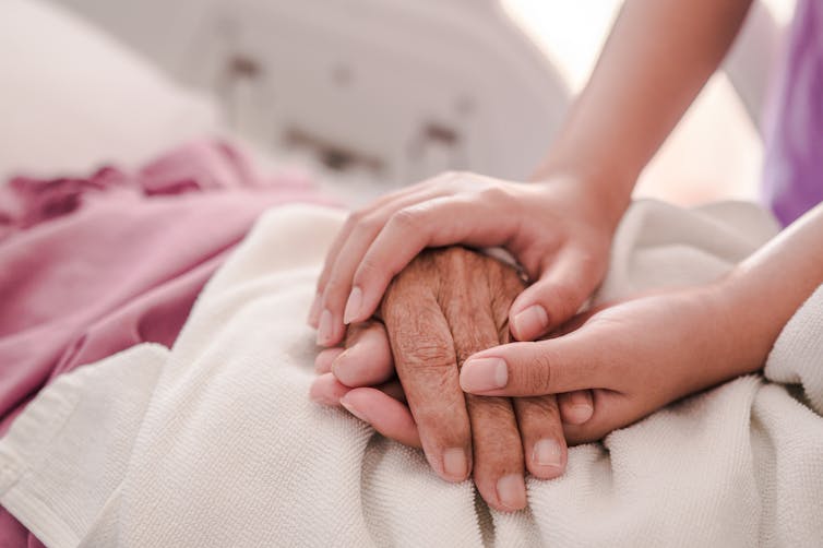 Two hands holding another person's hand.