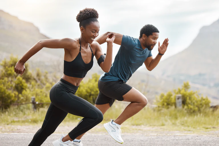 A young couple sprint down a road outdoors.