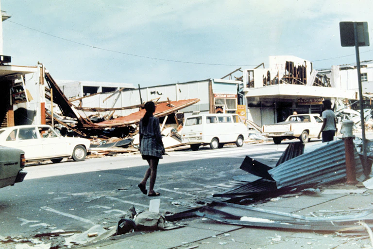 woman walks along damaged street