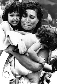 crying woman carries her two children