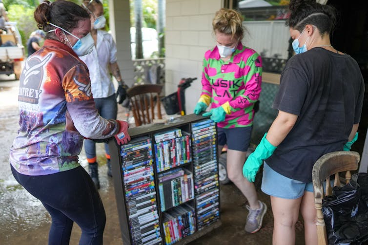 volunteers help carry furniture from flooded home