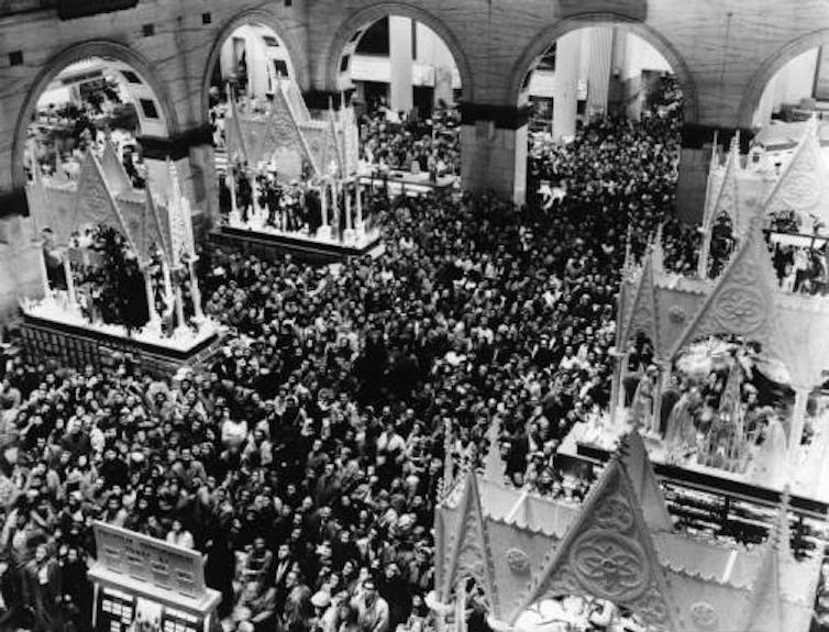Black and white photo of large crowd in indoor courtyard filled with holiday displays