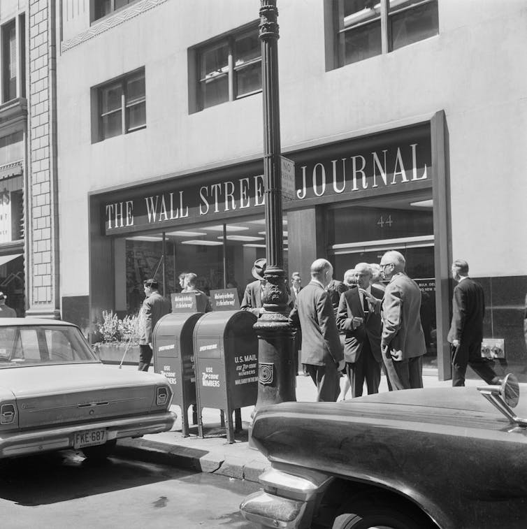 A black-and-white photo of several white men in suits standing in front of the Wall Street Journal's then-office.