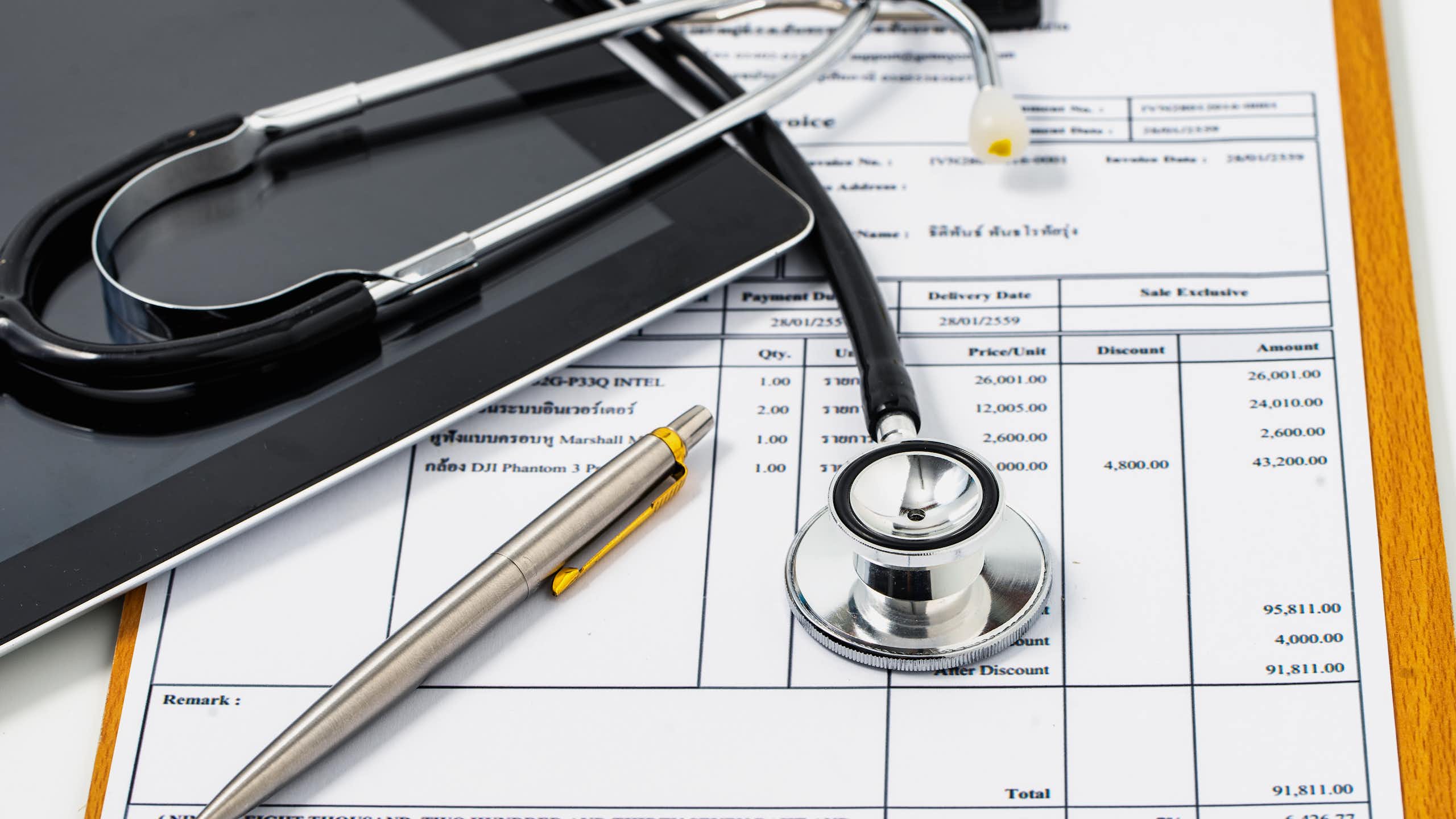 Stethoscope lying on top of excessively high medical bill.