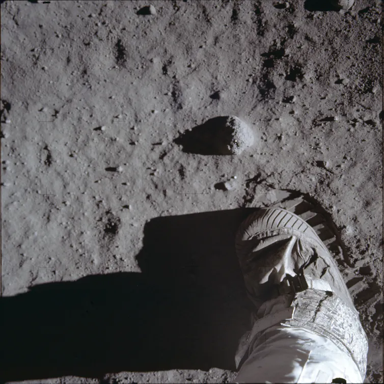 A photo, shown from above, of an astronaut's boot and boot print on the lunar surface.