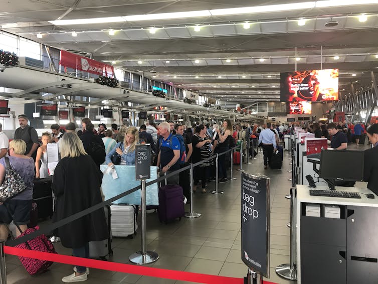 A long queue of people in an airport at Christmas time.
