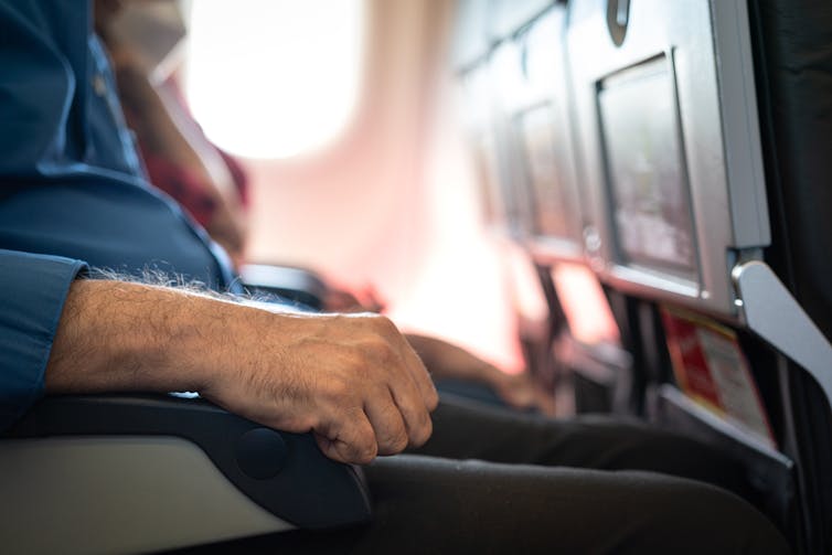 A man's arm on a plane armrest