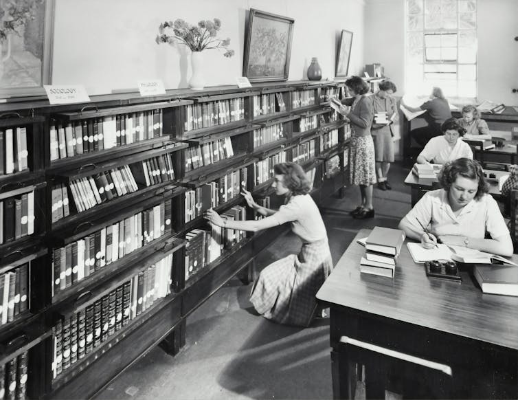 A black and white photo of women in a library, circa 1960s.