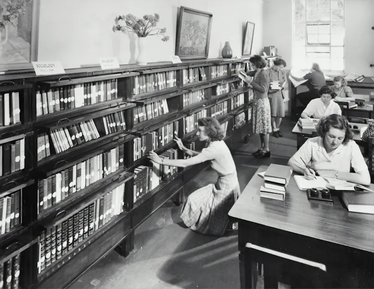 A black and white photo of women in a library, circa 1960s.