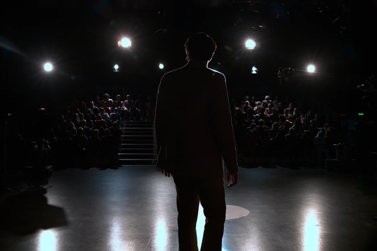 A man in silhouette in front of an audience.