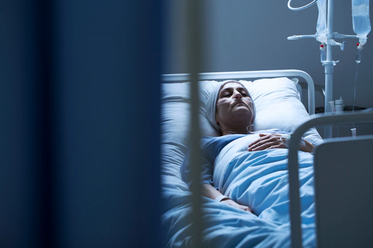 A woman with a head covering sleeping in a hospital bed.