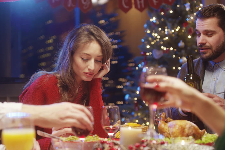 A woman looks sad while eating Christmas dinner.
