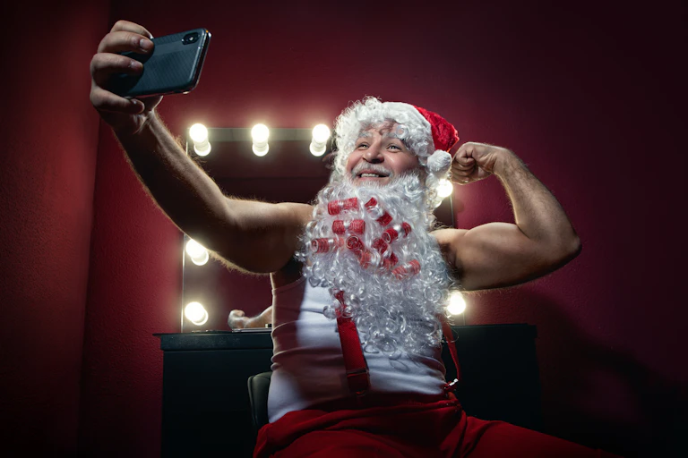 Narcissistic Santa Claus making selfie with mobile camera against the mirror.