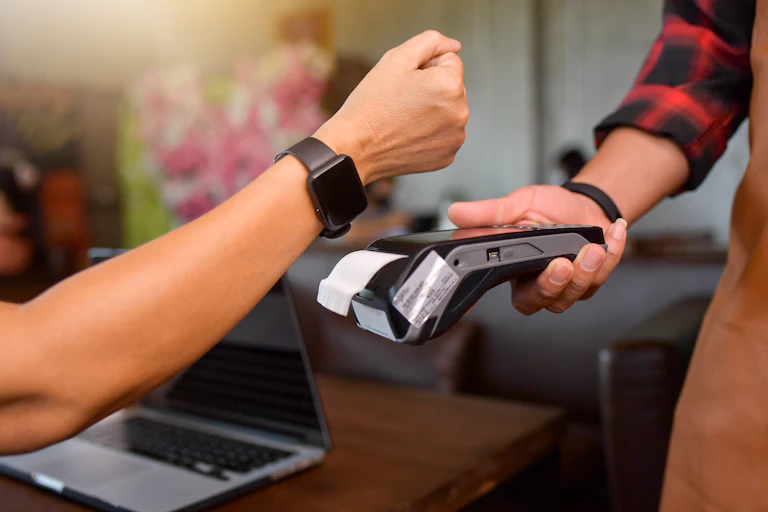 customer tapping their watch to make a mobile payment on a card reader