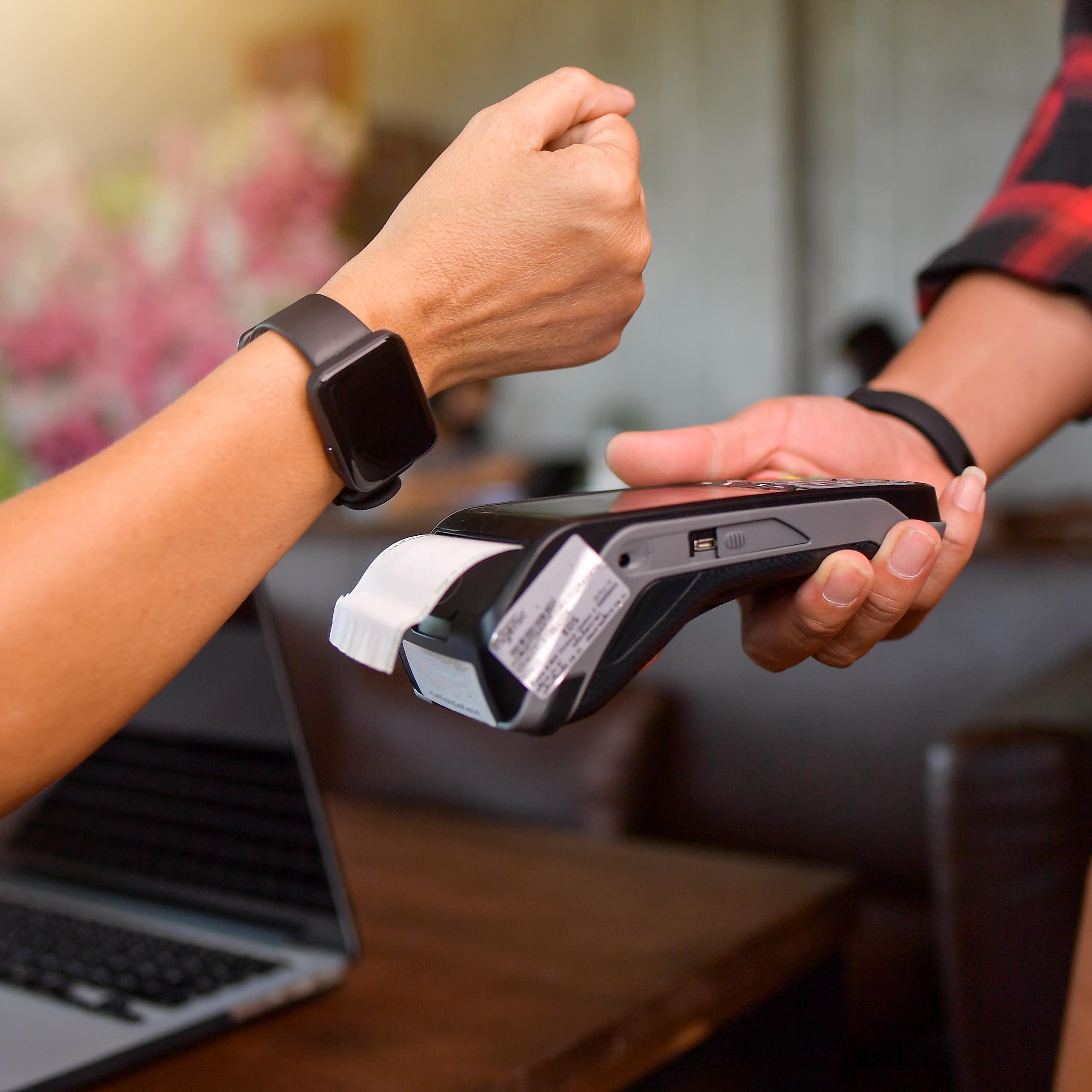 customer tapping their watch to make a mobile payment on a card reader