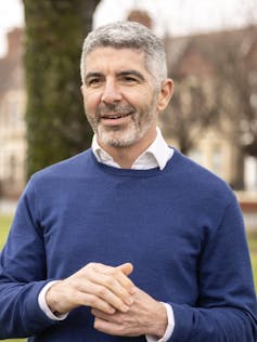 A portrait photo of a man in a blue sweater.