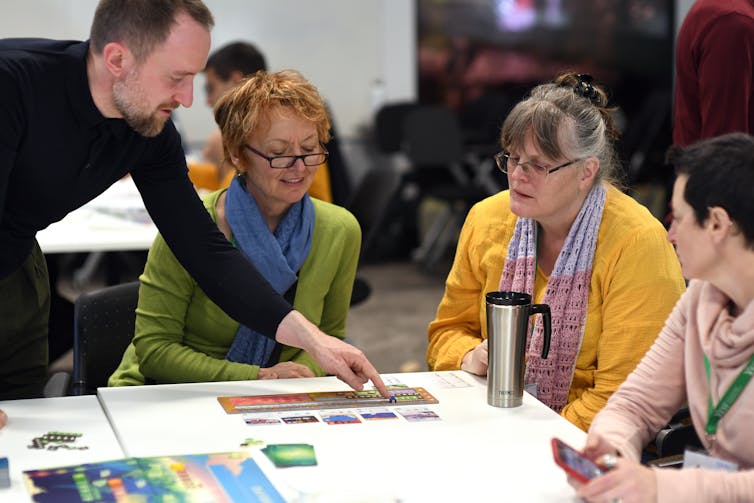 group of four adults around a table playing a climate board game