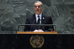A white man with thinning grey hair stands behind a United Nations lectern.