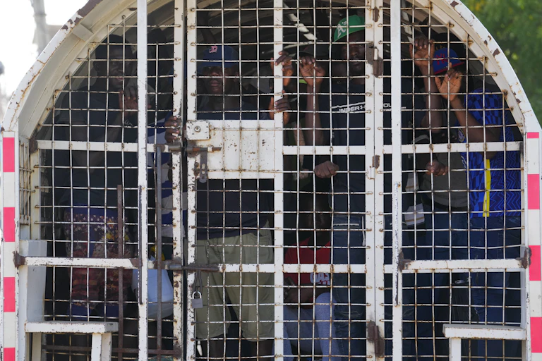 Black people inside a caged police vehicle.