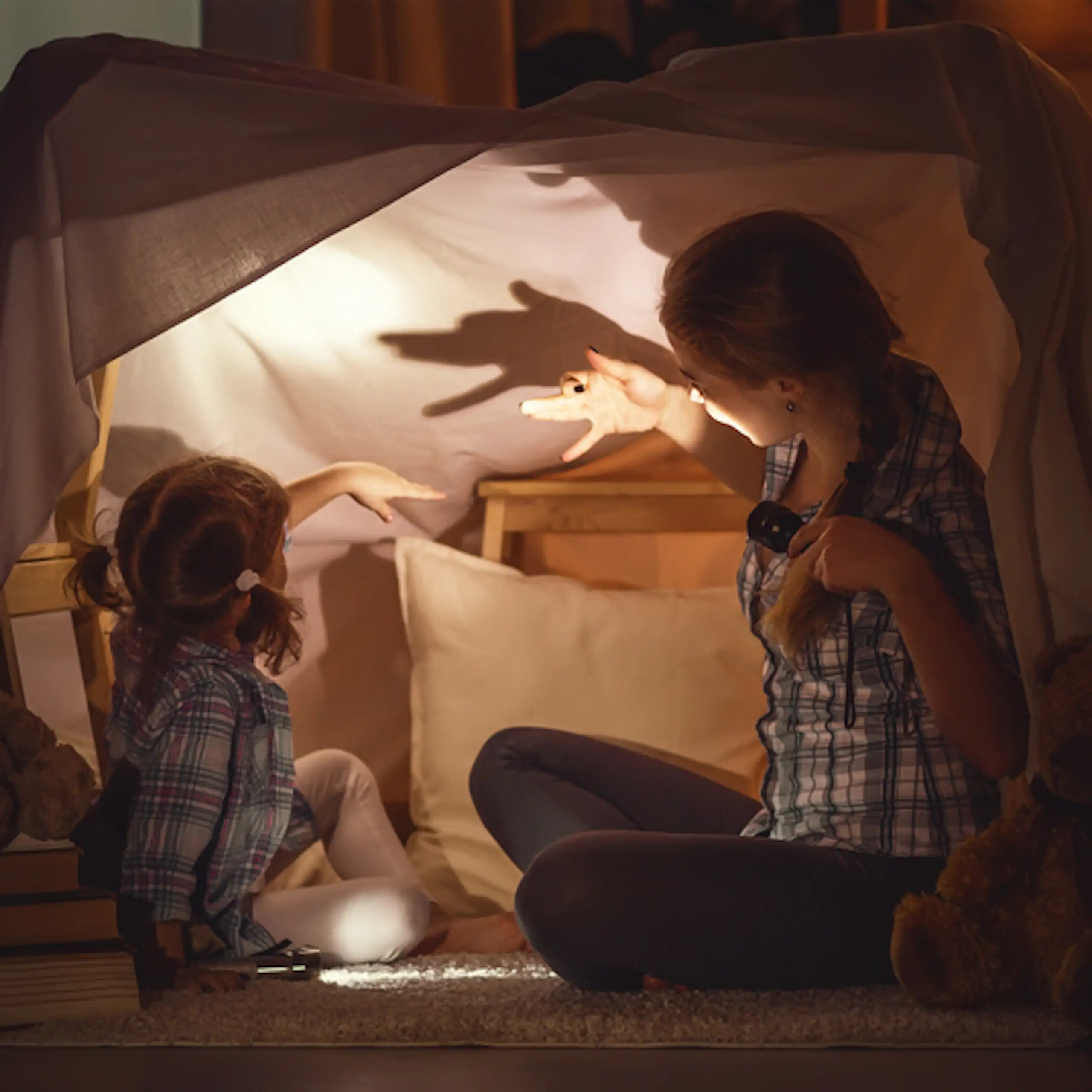 Une mère raconte une histoire à sa fille avec un théâtre d'ombres