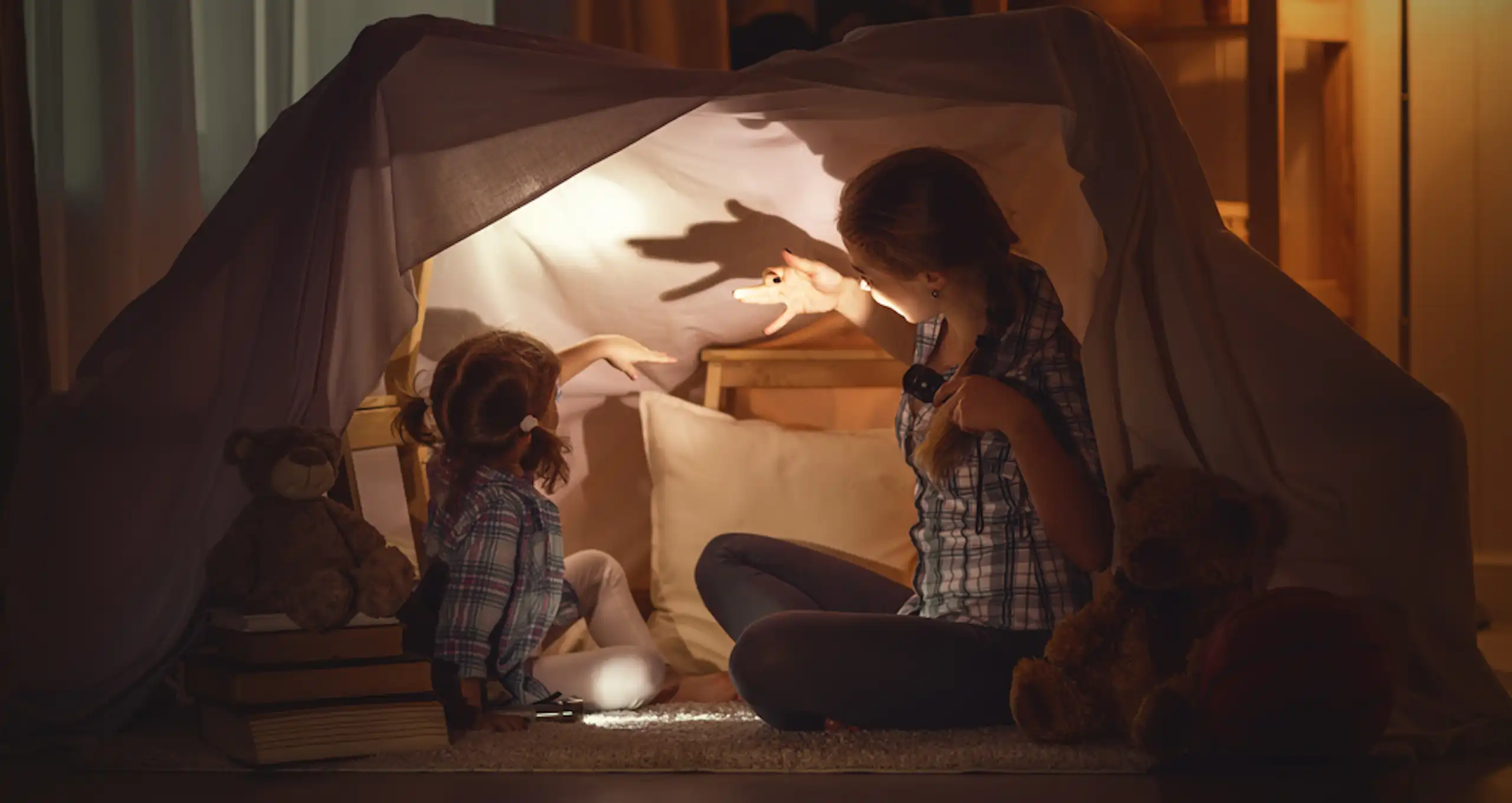 Une mère raconte une histoire à sa fille avec un théâtre d'ombres