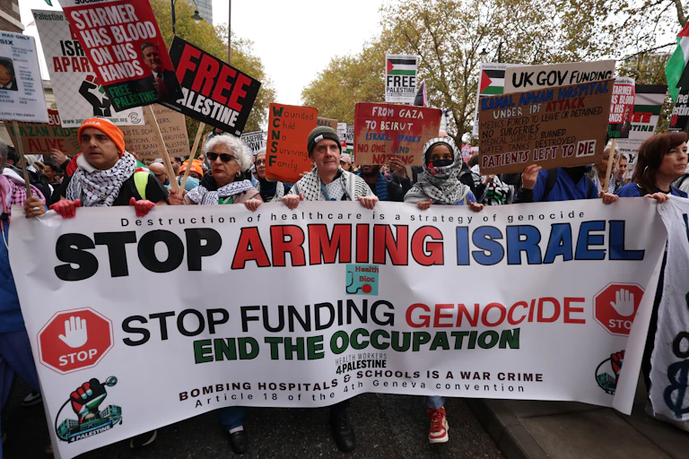 Protesters in London carry a banner calling on governments to stop supplying Israel with arms and claiming genocide in Gaza.