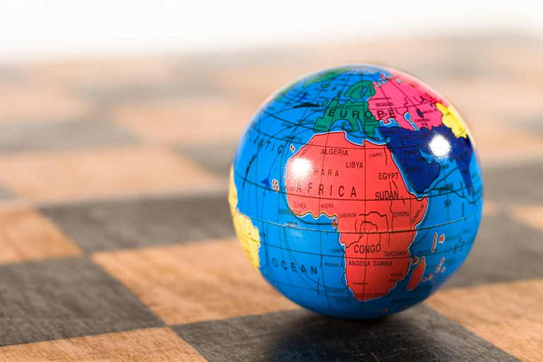 colourful globe planet sitting on wooden chessboard