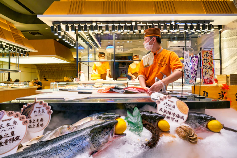 chinese chef preparing salmon in a restaurant kitchen