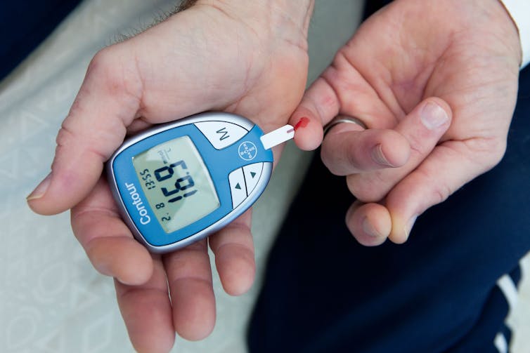 A person checking their blood glucose levels with an electronic device.