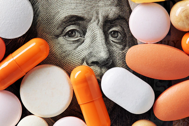 Assortment of pills covering all but the top half of Benjamin Franklin's face on 100 dollar bill