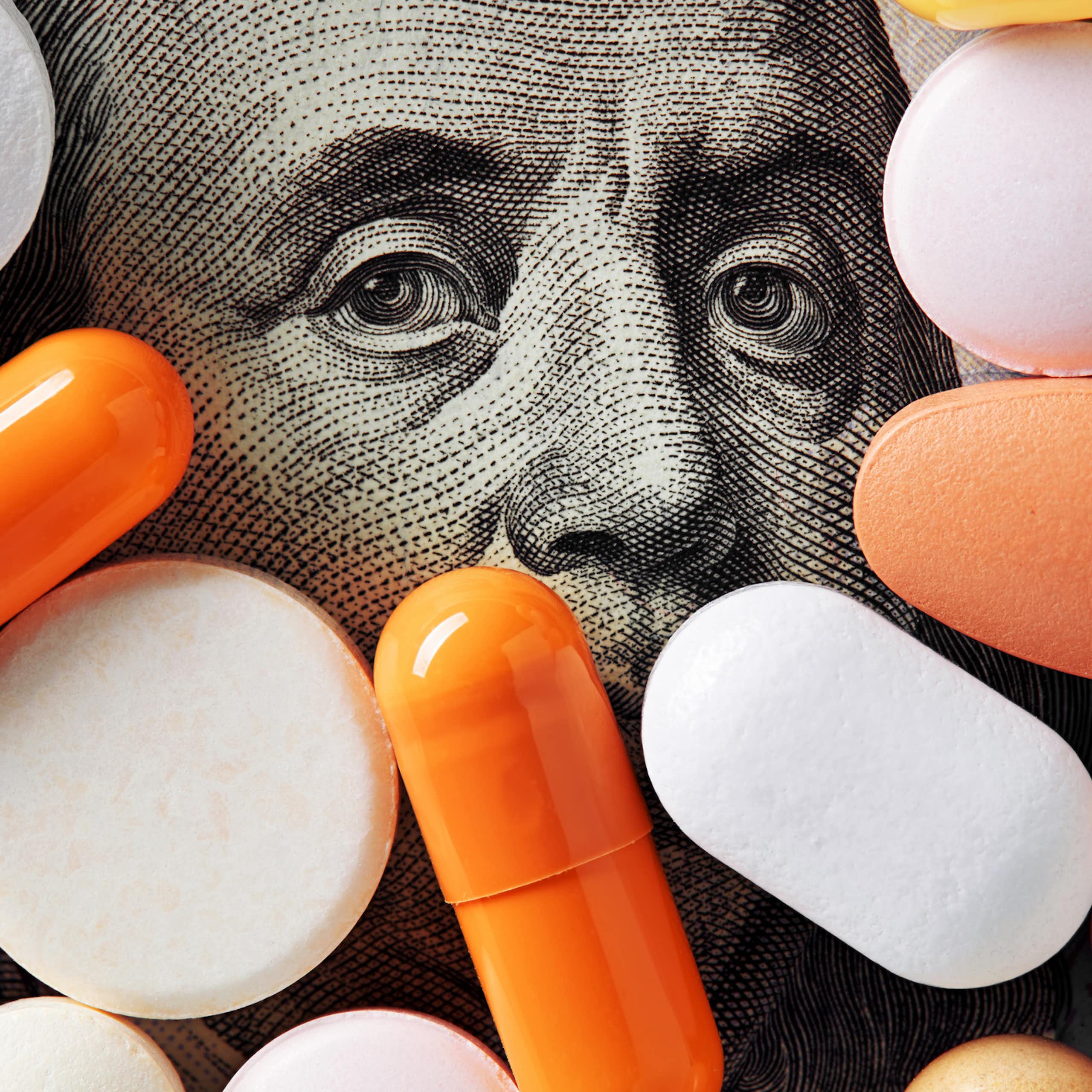 Assortment of pills covering all but the top half of Benjamin Franklin's face on 100 dollar bill