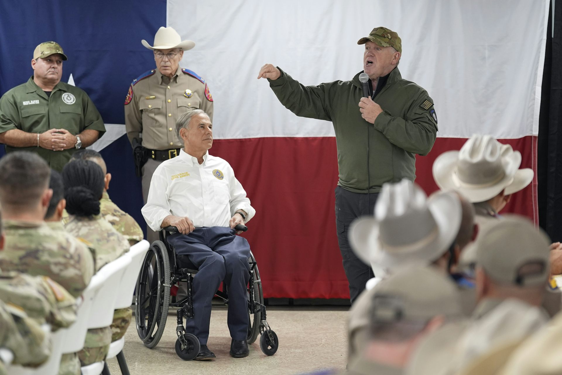 Texas Governor Greg Abbott looks at incoming U.S. Border Czar Tom Homan during a speech.