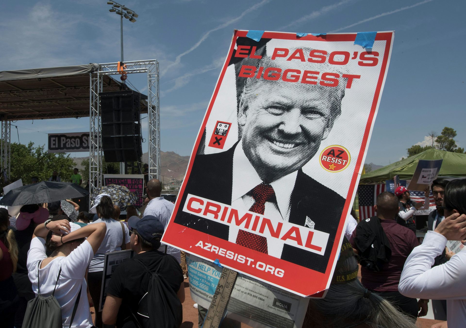 Protestors hold a poster criticizing Donald Trump.