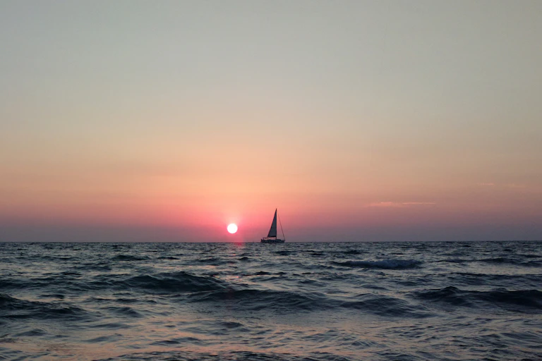 A boat on the water, with sunset in the background.