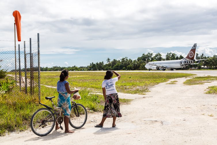 Kiribati women watch the plane arrive.