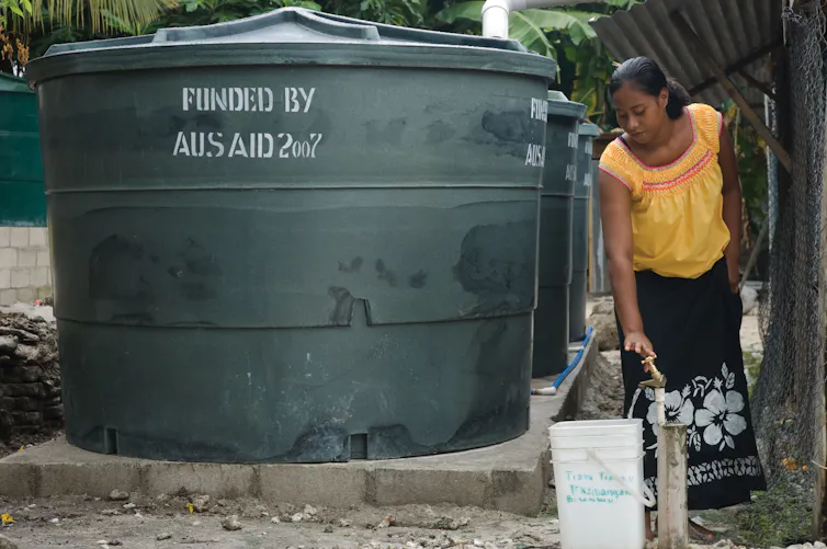 Woman stands next to water tank