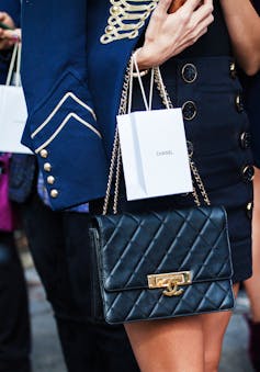 A woman in stylish luxury clothes holding a Chanel bag