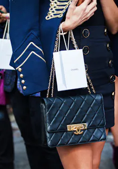 A woman in stylish luxury clothes holding a Chanel bag