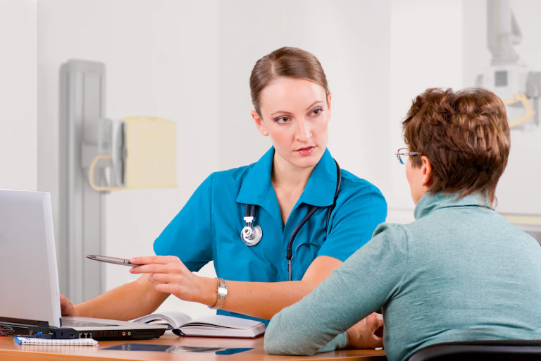 A young woman doctor talks to an older woman.