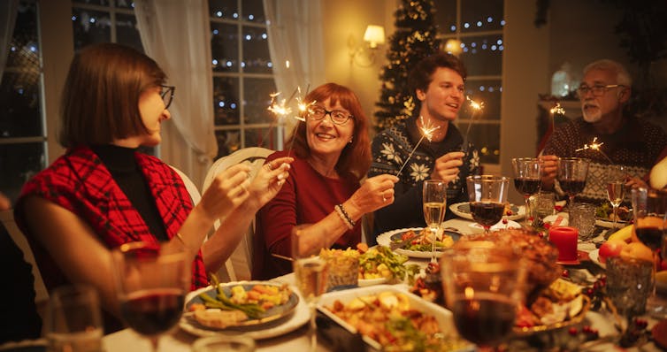 People around a festive table with sparklers.