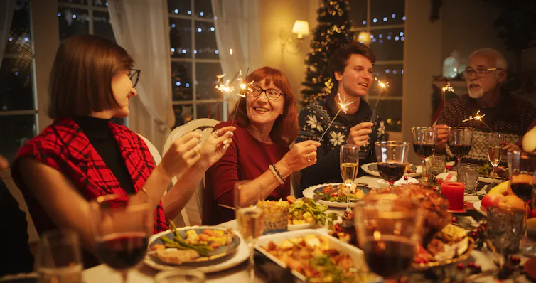 People around a festive table with sparklers.