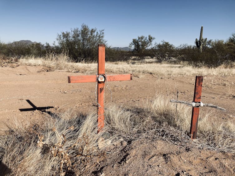 two wooden crosses marking graves in the desert