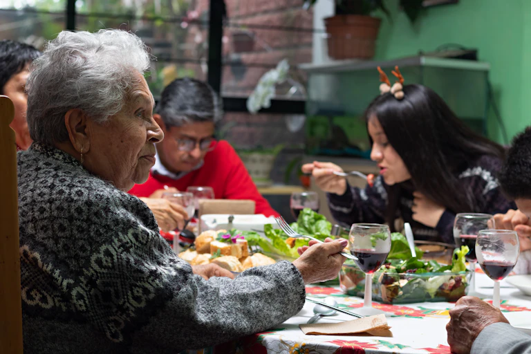 A senior woman at a festive meal appears pensive.