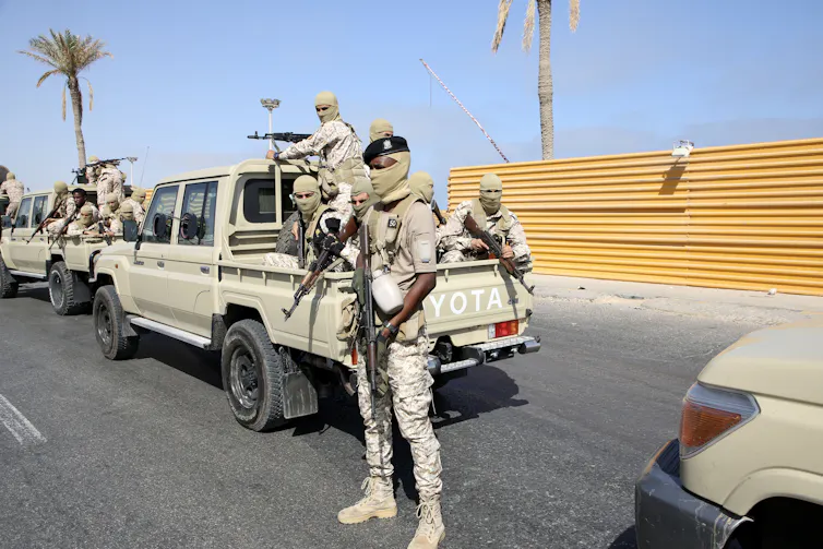 Libyan fighters in balaclavas sat in the back of a pickup truck.