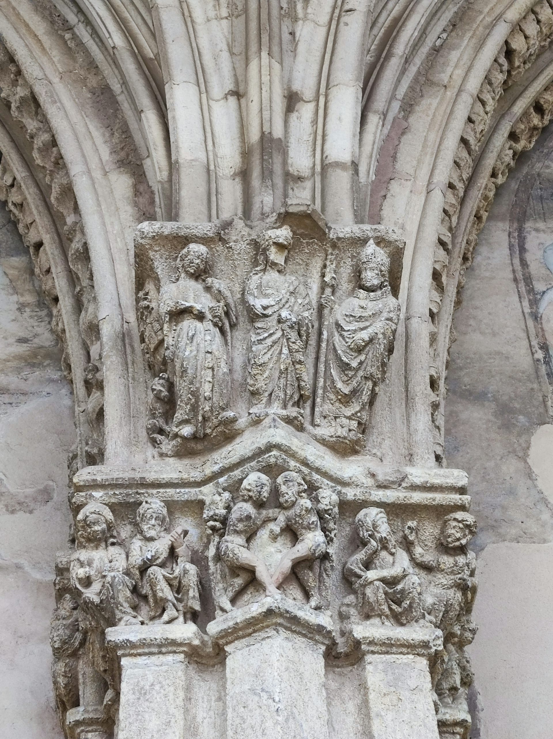 Capitel del claustro de León con tres figuras identificadas como Leonor de Guzmán (izquierda), Alfonso XI(centro) y  el obispo obispo Juan del Campo (izquierda).