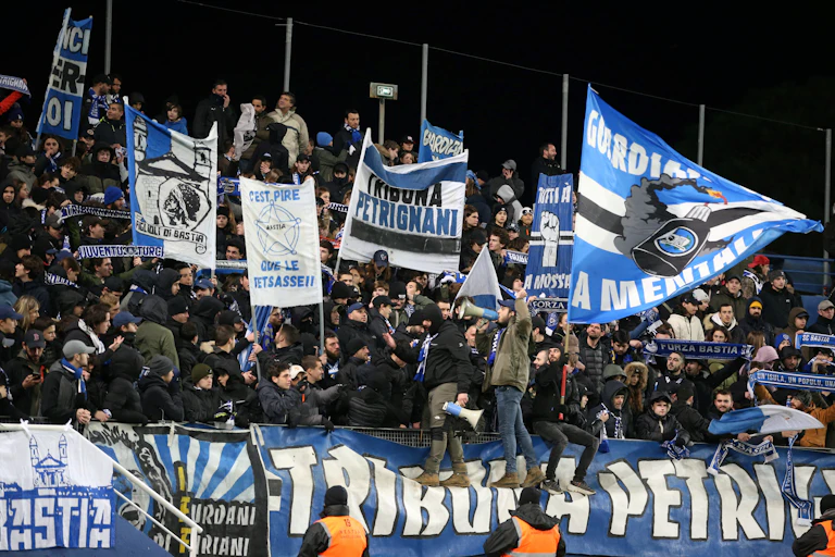 Des supporters agitent des drapeaux depuis les tribunes d'un match de football.