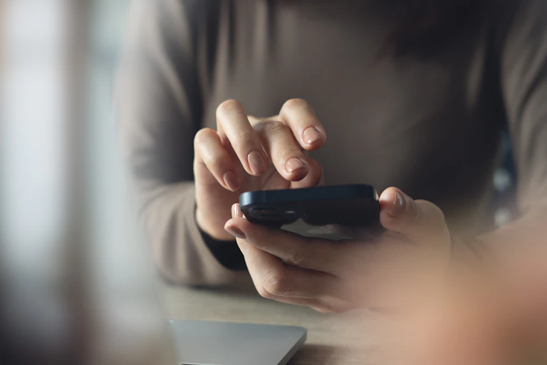 une femme ongle vernis pianote sur son smartphone
